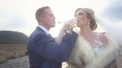 A bride and groom cross arms to drink champagne outside at their mountain elopement