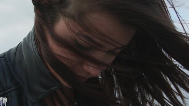 Sad girl looking down with messy hair in the wind