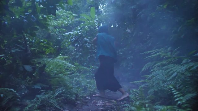 Barefoot man with hood covering his head shows off martial arts movements while holding a smoke grenade. PUSH IN.