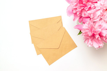 Handmade envelopes and a bouquet of peonies on a light gray background