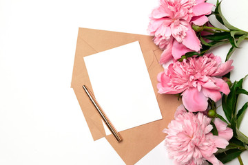 Wedding invitations, craft envelopes, pink flowers and green leaves on a white background