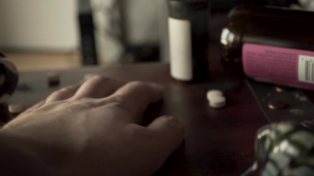Addict grabbing prescription drug pills with his hand in slow motion