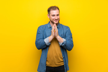 Blonde man over isolated yellow wall scheming something