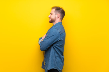 Blonde man over isolated yellow wall in lateral position