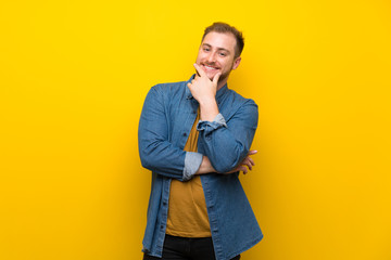 Blonde man over isolated yellow wall smiling