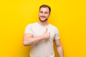 Handsome man over yellow background giving a thumbs up gesture