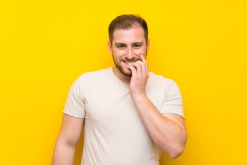 Handsome man over yellow background nervous and scared