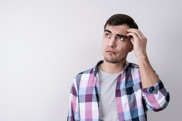 Portrait of a brooding young man on a gray background with a copy of space