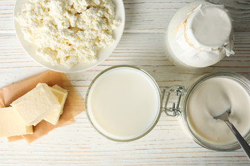 Different dairy products on white wooden background, top view