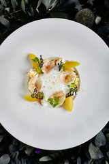 Exquisite Serving Restaurant Plate of Tiger Shrimps with Avocado Tartare and Sweet Chili under the Foam of Lime Juice Top View. Macro Photo of King Prawns on Dark Leaves and Flowers Background