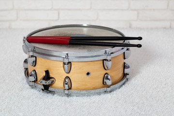 Snare drum with drum sticks on brick wall background