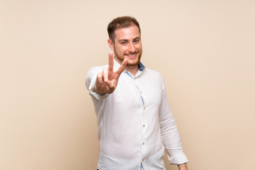 Blonde man over isolated background smiling and showing victory sign