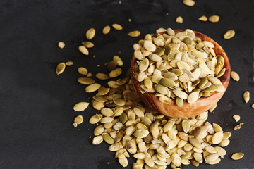 Raw pumpkin seeds on black slate background