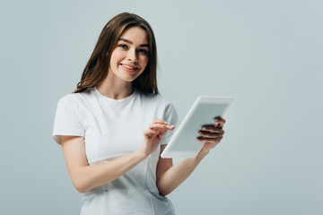 Fototapeta premium happy girl in white t-shirt holding digital tablet isolated on grey