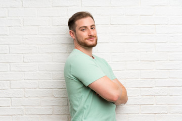 Blonde man over brick wall laughing