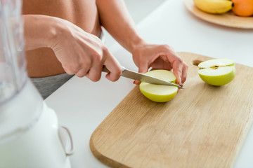 cropped view of girl cutting tasty apple on chopping board