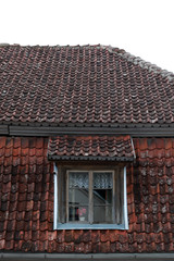 red tiled roof and one wooden window with curtains