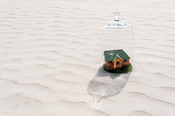 toy house with a lawn under a glass dome in the desert