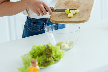 cropped view of woman putting sliced apple in bowl