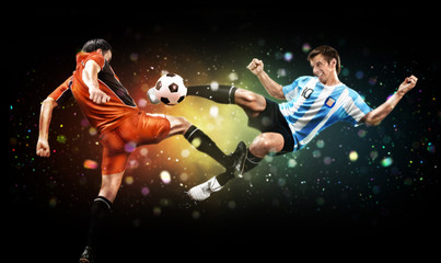 Soccer and sport concept. Two players in action to kick the ball at the football game on dark background with lights and bokeh