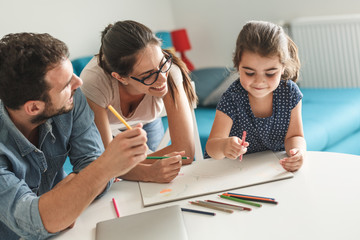 Obraz premium Father and mother teach daughter to draw.They sitting in living room.Education and family concept.