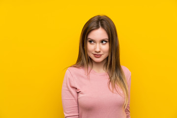 Obraz premium Teenager girl over isolated yellow background standing and looking to the side