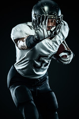 Fototapeta na wymiar American football sportsman player in helmet isolated run in action on black background. Sport and motivation wallpaper. Team sports,