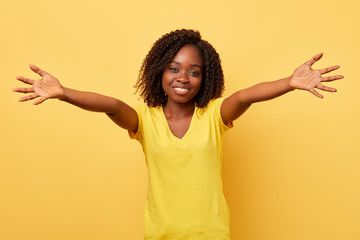 happy charming young girl with outstretched hands wants to embrace you isolated in yellow...