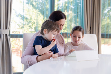 Grandma entertaining her little grandchildren with a tablet computer game