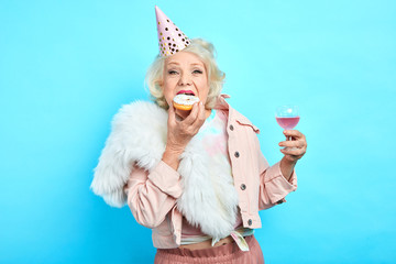 glamour crazy funny grandmother in stylish clothes celebrating her anniversary alone. close up portrait. isolated blue background. studio shot - 283999783
