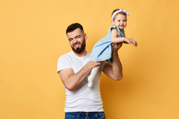 Young unhappy bearded dad holding daughter in hands, stink coming from his daughter. close up photo. isolated backgrounf. difficult parenthood.