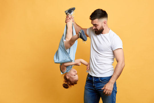 angry frustrated guy holding his naughty sister's leg and scolding her. problem, conflict, isolated yellow background. copy space