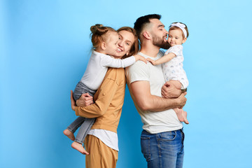 caring parents hugging their children, expressing love, warm feeling. close up photo. isolated blue background. studio shot - 284001104