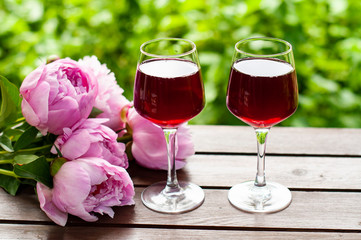Glass of red wine,  bouquet of flowers on  garden background