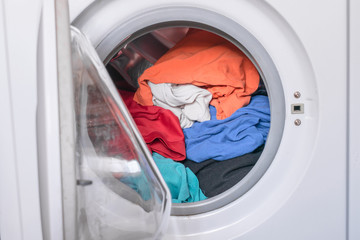 Open the door of the washing machine. Dirty clothes are folded into the washer drum. The concept of cleaning and cleanliness.
