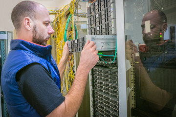 Technician repairs the central router. System administrator installs a new server in a modern data...