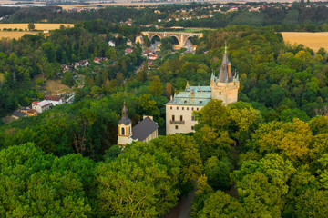 Fototapeta na wymiar Aerial View of Old Castle in Green Wood With Old Bridge on the Background