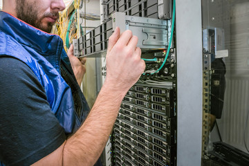 Service work on the technical platform. The man replaces the server in the rack. The engineer...