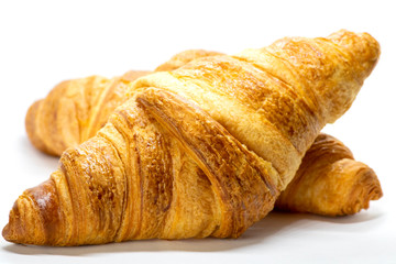 Freshly baked croissant with flaky texture on white background. 
