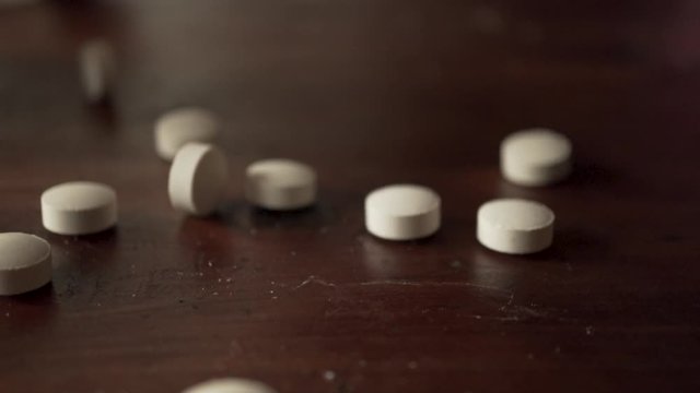 Closeup falling prescription pills, drug addiction concept