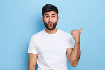 emotional attractive Arab man pointing aside, place for advert, text. direction, look here,...
