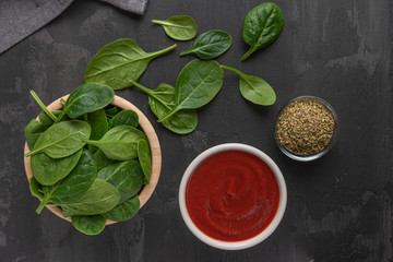 Italian cuisine. Mediterranean cuisine. Spinach leaves, tomato, oregano, tomato sauce and olives on table. Recipe Ingredients