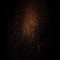 Fototapeta na wymiar Cocoa powder sifting isolated on black background. Chocolate dust on black background
