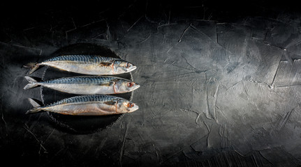 Fresh raw herrings served on dark background