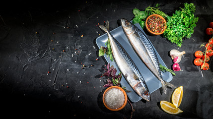 Fresh raw herrings with herbs, spices, onion and parsley on dark background. Top view with copy...