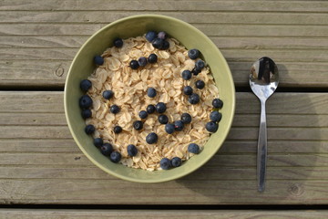 oatmeal with fresh blueberries. organic cereals in the green bowl on the wooden background. vegan breakfast.