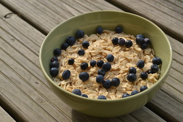 oatmeal with fresh blueberries. organic cereals in the green bowl on the wooden background. vegan breakfast.