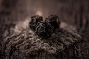 grains of black pepper on jute fabric close-up