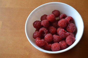 raspberries in the small white bowl. fresh organic berries.