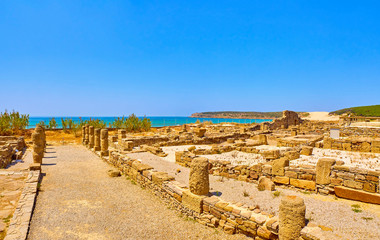 Street of the Columns of Baelo Claudia Archaeological Site, with the Bolonia Beach in the background. Tarifa, Cadiz. Andalusia, Spain.